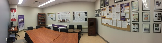 Collaborative meeting space with tables and chairws, featuring past projects as artwork on walls.